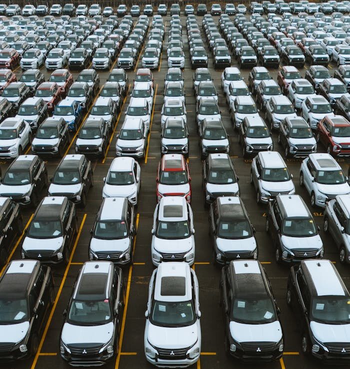 Aerial view of numerous cars in a parking lot, showcasing lined automobiles for sale or storage.