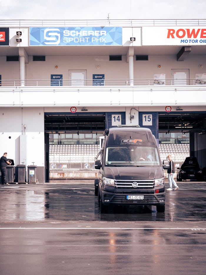 Volkswagen van parked at Nürburgring garage under bright sun, capturing motorsport ambiance.