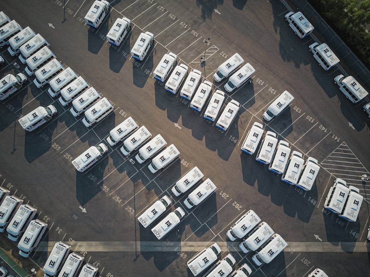 Aerial drone shot of neatly organized vans in a large parking lot.
