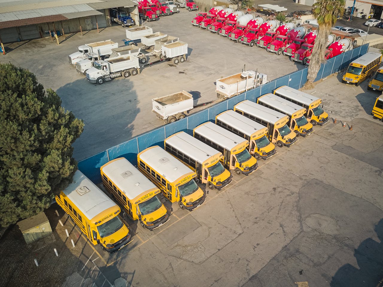 Aerial view of school buses and trucks parked in an industrial lot.